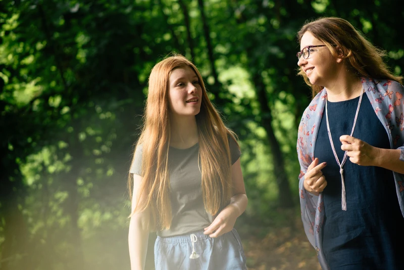 Frau geht mit M&auml;dchen im wald spazieren.