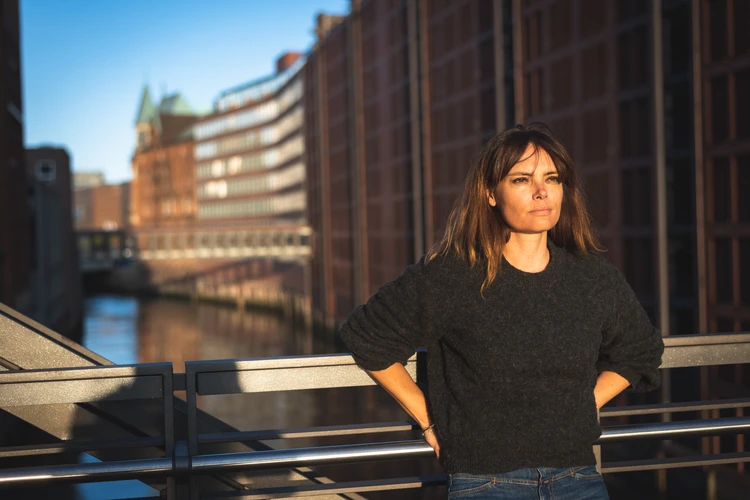 Frau steht auf einer br&uuml;cke und schaut zur sonne
