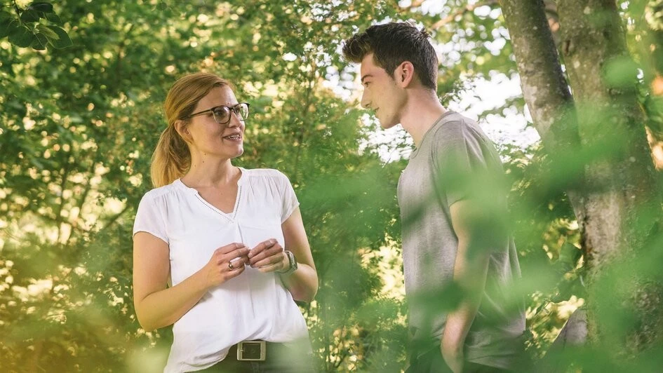 Zwei Menschen unterhalten sich unter einem Baum